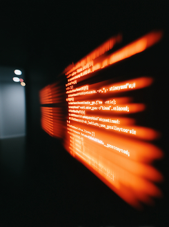Blurred red glowing computer code on a dark background in a dimly lit room.